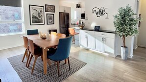 A modern kitchen with white cabinets, a black refrigerator, and a dining area with a wooden table and blue chairs. - Downtown Dayton townhouse with private garage AND rooftop patio! (Dayton)