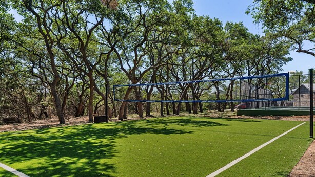 Un terrain de sport doté d’une pelouse artificielle, entouré d’arbres.