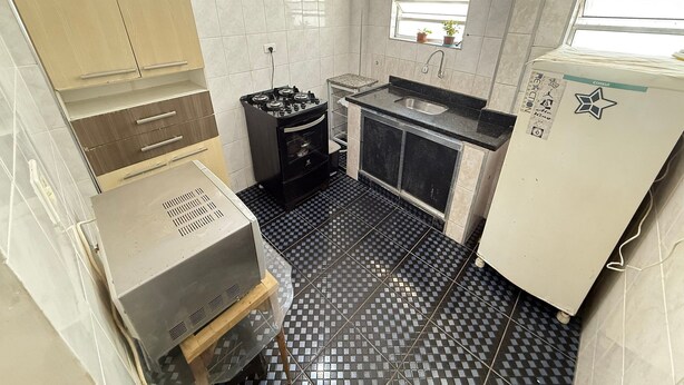 A compact kitchen with a gas stove, a sink, and a refrigerator. - Pé na Areia Praia da Tupi (Praia Grande)