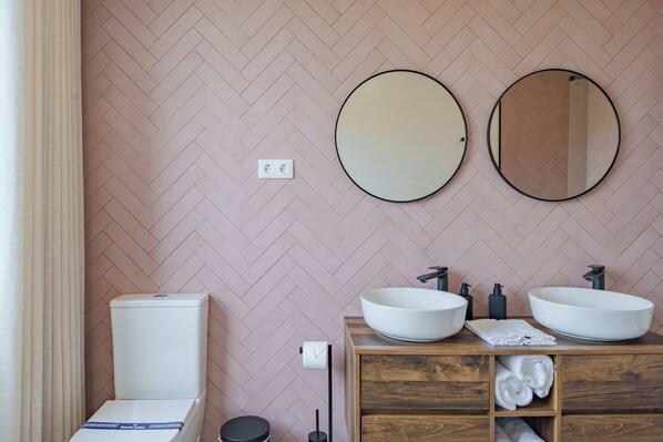 A bathroom with a herringbone-patterned wall, two round mirrors, a wooden vanity with two sinks, and a toilet. - Feel Discovery Casal do Temporão Douro (Peso da Régua)