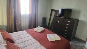 A hotel room with a bed, a TV on a cabinet, and a speaker. - Hena Apart I (Esquel)