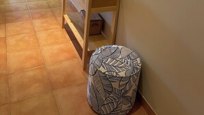 A hallway with a wooden console table, a round ottoman, a mirror, and a vase with dried plants. - Appart. T2 Les Issambres 400 m from beaches and port (Roquebrune-sur-Argens)