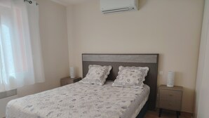 A neatly made bed with a floral bedspread, two matching pillows, and two bedside tables with lamps. - Appart. T2 Les Issambres 400 m from beaches and port (Roquebrune-sur-Argens)
