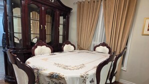 A dining room with a round table, six chairs, a large wooden cabinet with glass doors, and beige curtains. - 3-Bedrooms House in Mississauga with WiFi, AC, Parking. Main floor (Mississauga)