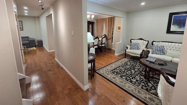 A spacious living room with a sofa set, a coffee table, and a patterned rug. A staircase leads to another room, and a dining area is visible in the background. - 3-Bedrooms House in Mississauga with WiFi, AC, Parking. Main floor (Mississauga)