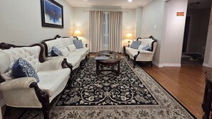 A living room with two white sofas with dark wooden legs, a glass coffee table, and a patterned rug. - 3-Bedrooms House in Mississauga with WiFi, AC, Parking. Main floor (Mississauga)