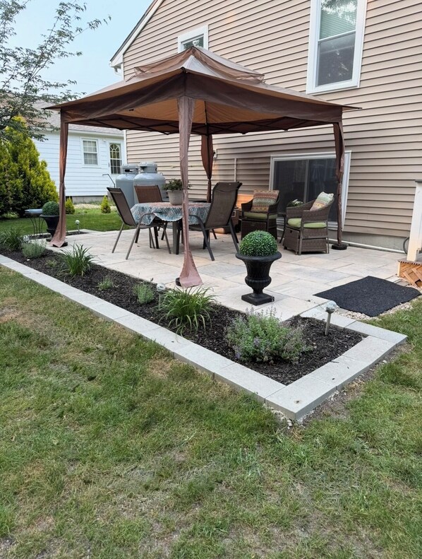 A patio with a covered seating area, outdoor furniture, and a garden bed with plants.