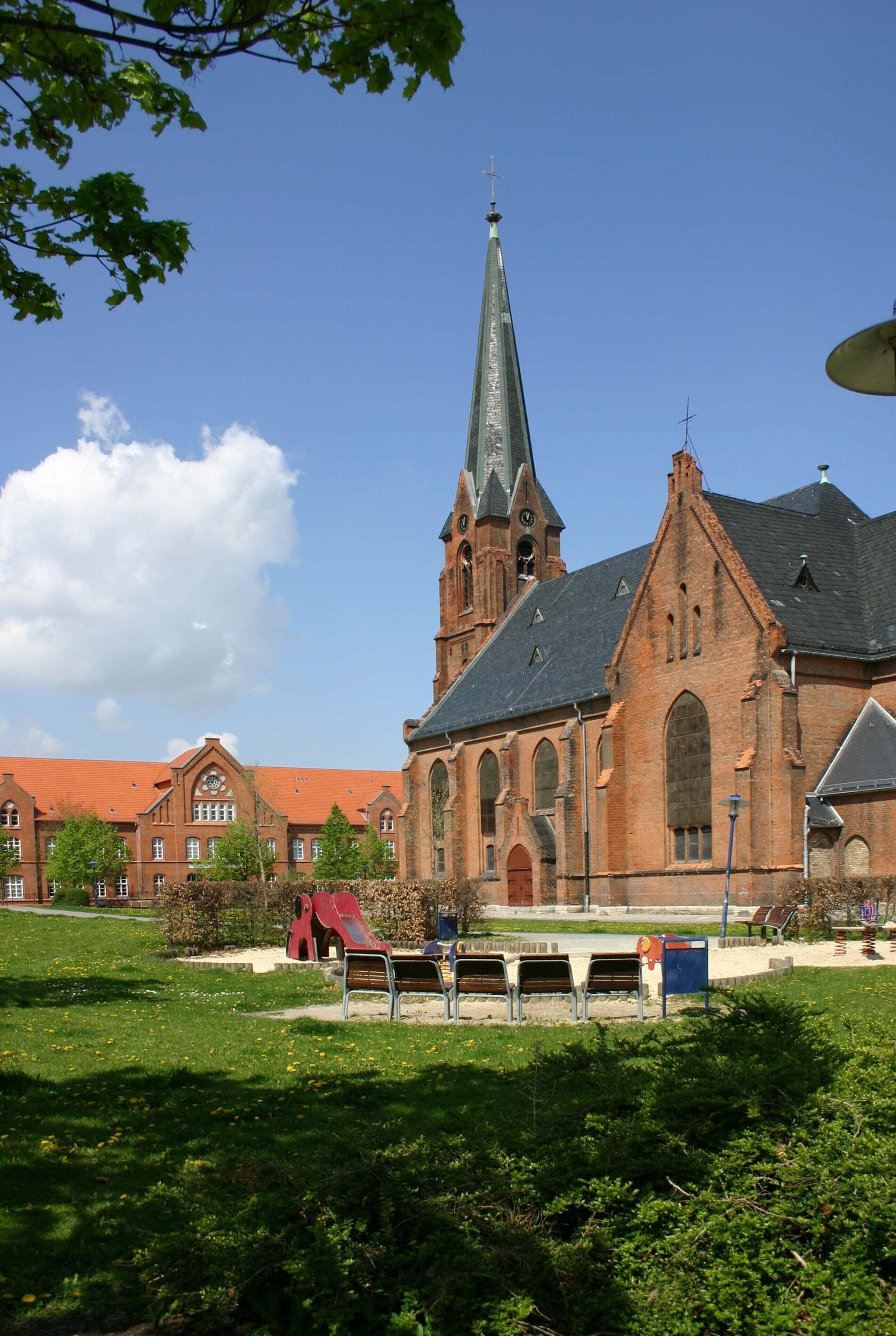 Une grande église en briques, dotée d’un haut clocher et d’un toit rouge.