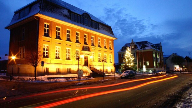 Un edificio grande e iluminado, con muchas ventanas y un techo cubierto de nieve.