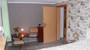 Una habitación de hotel con una cama, una mesita de noche con lámpara, una silla y un armario.