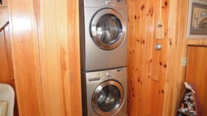 Eine kompakte, zweiteilige Waschmaschine mit Frontlader in einem Raum mit Holzoptik.