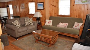 Ein Wohnzimmer mit Holzwänden, einer Couch, einem Couchtisch und einem Fernseher.