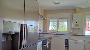 A modern kitchen with stainless steel appliances, a built-in oven, a washing machine, and a dishwasher.