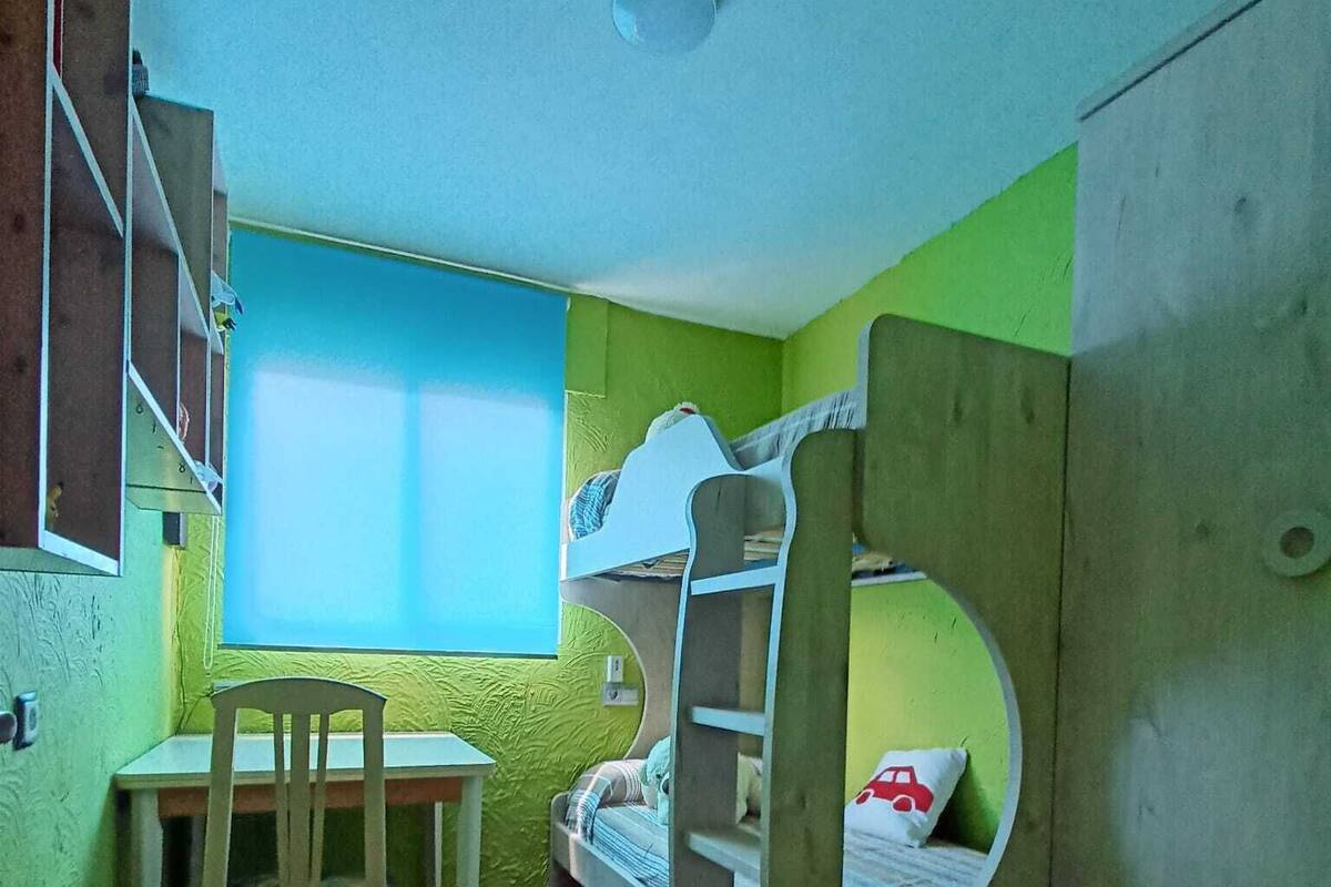 A small, compact room with bunk beds, a desk, and a chair.