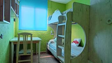 Una habitación pequeña y funcional con literas, un escritorio y una silla.