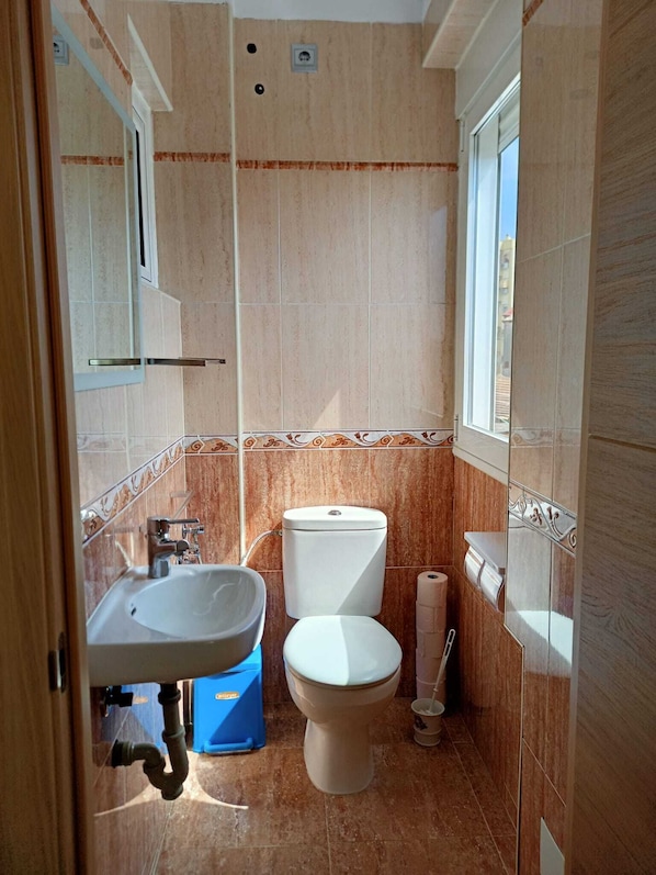 Un baño pequeño con inodoro, lavamanos y ventana.