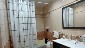 A bathroom with a shower, toilet, bidet, and sink.