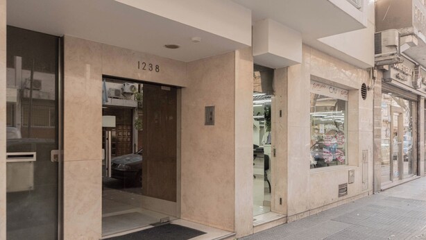 Une entrée d’immeuble avec le numéro « 1238 » au-dessus de la porte, une porte en verre et une petite marche menant à l’entrée.
