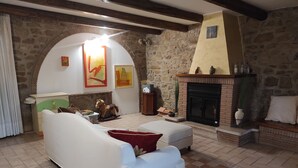 Un salon chaleureux avec une cheminée en pierre, un canapé et une statue de cheval décorative.