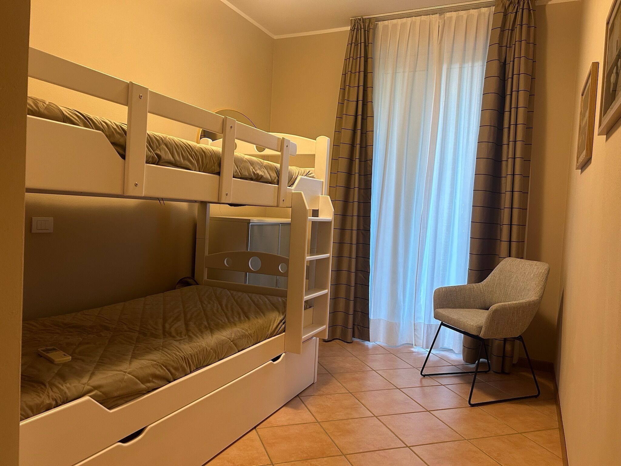 Una camera con letto a castello, una sedia e tende.