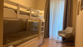 Una camera con letto a castello, una sedia e tende.
