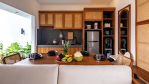 A modern kitchen with wooden cabinets, a refrigerator, and a dining area with a table set for two. - [Brand New] Serene Bali Villa w/ Private Pool – Tropical Escape in Canggu (Bali)