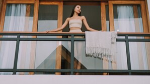 A balcony with a wooden ceiling, large windows with curtains, and a person leaning on the railing. - [Brand New] Serene Bali Villa w/ Private Pool – Tropical Escape in Canggu (Bali)