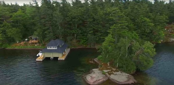 A houseboat on a lake surrounded by dense forest.