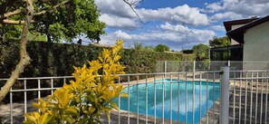 Relax by the pool surrounded by lush gardens and a modern house.