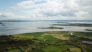 A panoramic view of a coastal landscape with multiple islands and a winding road through green fields. - Scenic Cottage on the Shannon Estuary Way (Ennis)