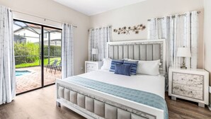 Un dormitorio con una cama grande, un ventanal de vidrio que da a un patio y una mesita de noche con una lámpara.