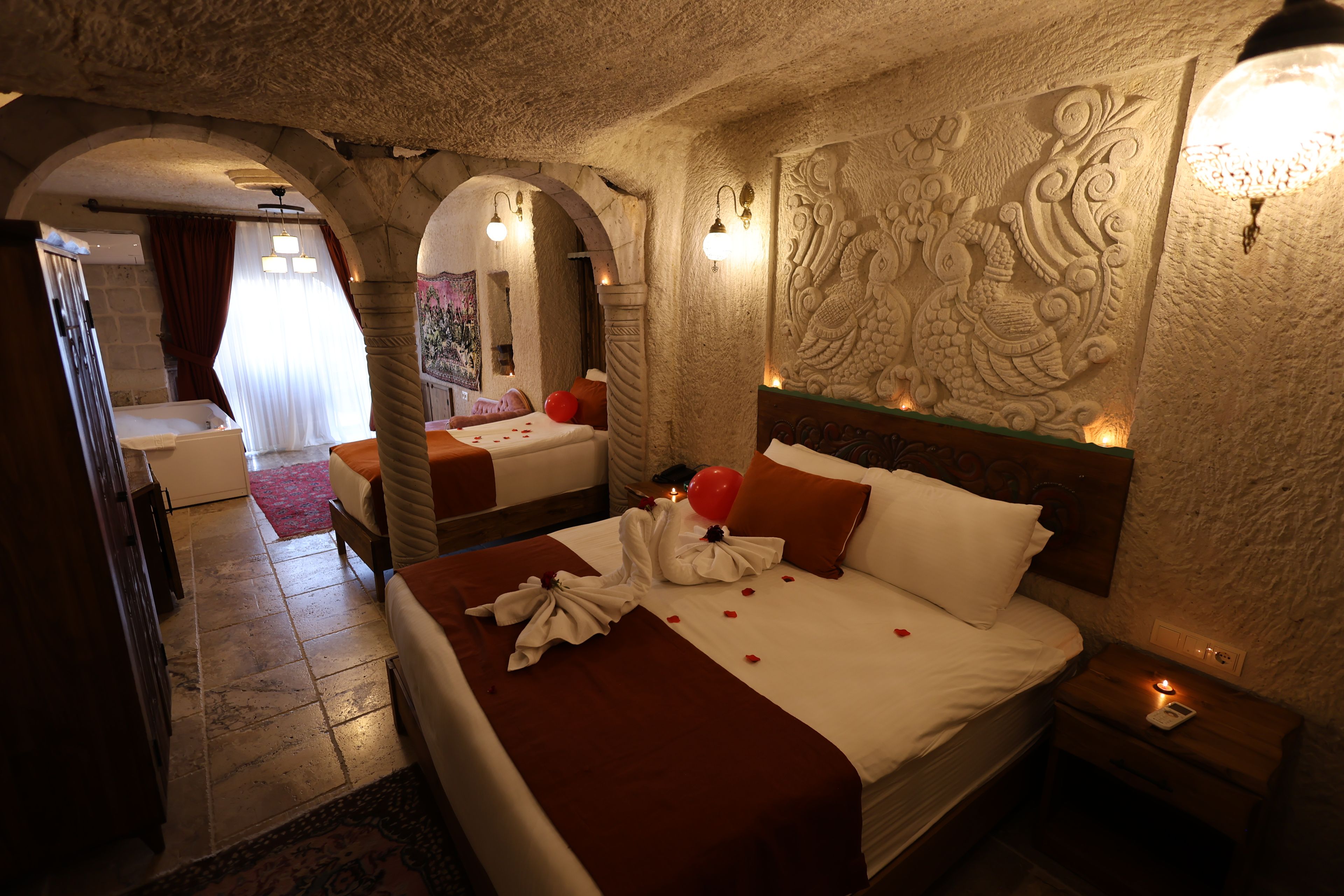 Habitación de hotel con una cama grande, dos camas más pequeñas, una zona de estar y una decoración de pared.