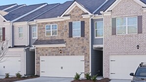 A row of townhouses with stone facades, multiple garage doors, and a clear sky.