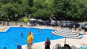 Una piscina con persone, un'area recintata e una foresta sullo sfondo.