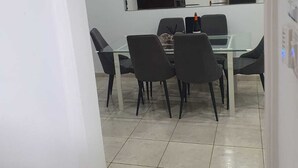 Un salón de conferencias con una mesa de vidrio, sillas negras y un equipo de aire acondicionado en la pared.