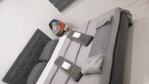 Una cama bien hecha con ropa de cama gris y un cabecero acolchado.