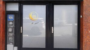Μια πρόσοψη κτιρίου με μια μαύρη είσοδο και μια γυάλινη πόρτα που φέρει ένα λογότυπο και την επιγραφή «en part».