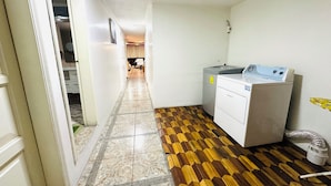 Un pasillo con piso estampado que conduce a una habitación con lavadora y radiador.