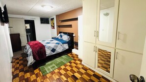 Un dormitorio con cama, armario y baño al fondo.