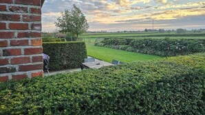 Un jardin aménagé avec un mur en briques, une table en bois et des chaises.