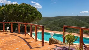 A pool with a wooden deck and a view of hills.