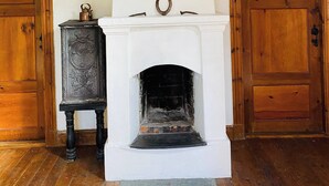 A room with a white fireplace, wooden beams, and two wooden doors. - Cottage for Rent in Urshult (Urshult)