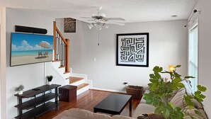 Ein Wohnzimmer mit Sofa, Couchtisch, Fernseher und einer Treppe.