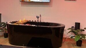 A modern room with a large black bathtub, a flat-screen TV mounted on the wall, and a potted plant. - Magnificent Imperial suite for 2 people breakfast included free prosecco (Palermo)