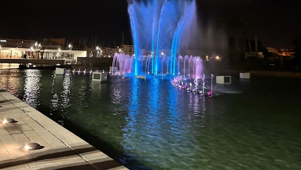 A nighttime view of a water fountain with illuminated jets, a dock, and a cityscape in the background. - Magnificent Imperial suite for 2 people breakfast included free prosecco (Palermo)