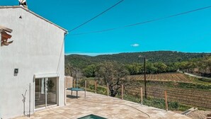A modern house with a swimming pool, a satellite dish, and a view of vineyards in the background.