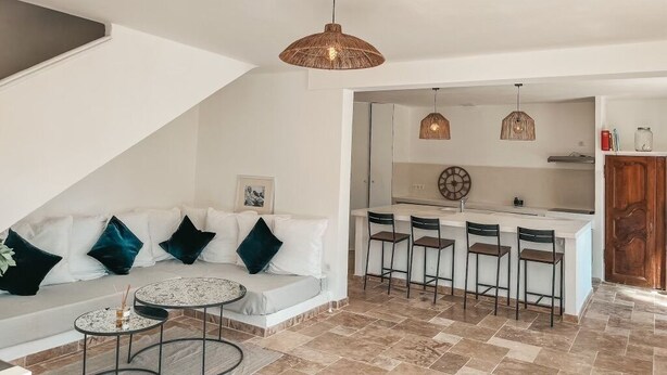 A modern living room with a sofa, a small round table, and a kitchen area with a bar.