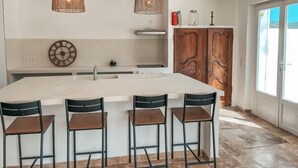 A modern kitchen with a large island, pendant lights, and bar stools.