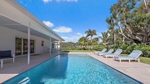 A swimming pool with lounge chairs and a covered patio area.