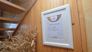 Ein gerahmtes Gastfreundschaftszertifikat an einer Holzwand.